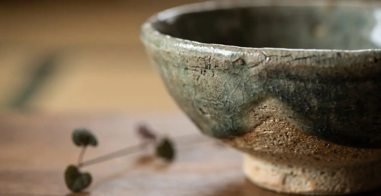 Gros plan macro sur une céramique japonaise artisanale avec détails de texture et arrangement floral minimaliste