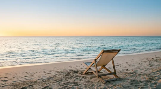Vue panoramique paisible d'une plage au coucher du soleil avec chaise longue et horizon marin