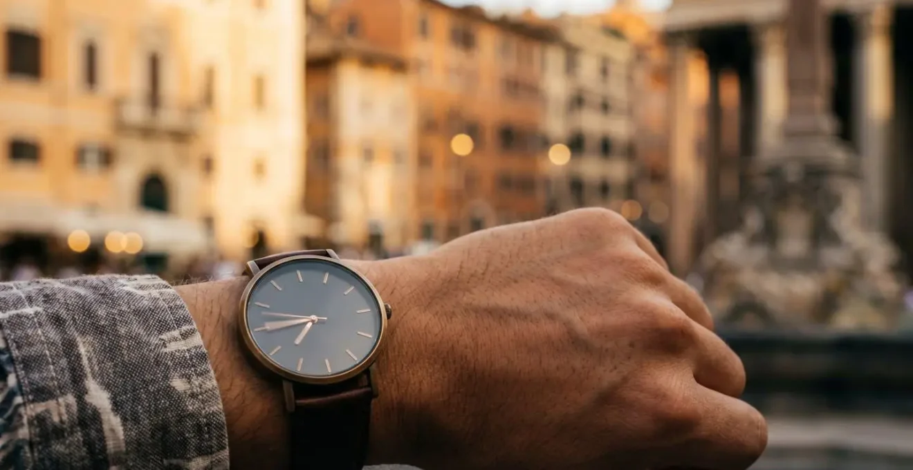 Main avec montre élégante pointant vers horizon urbain flou suggérant gestion du temps en voyage