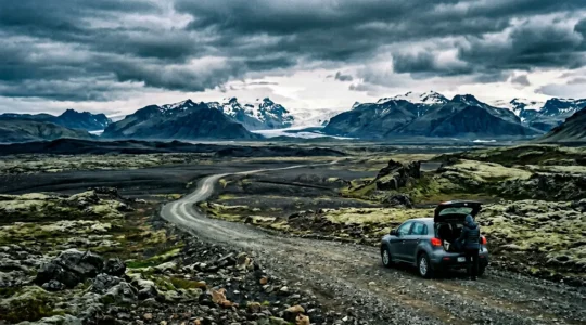 Voyageur planifiant son budget devant un paysage islandais avec glaciers et montagnes volcaniques